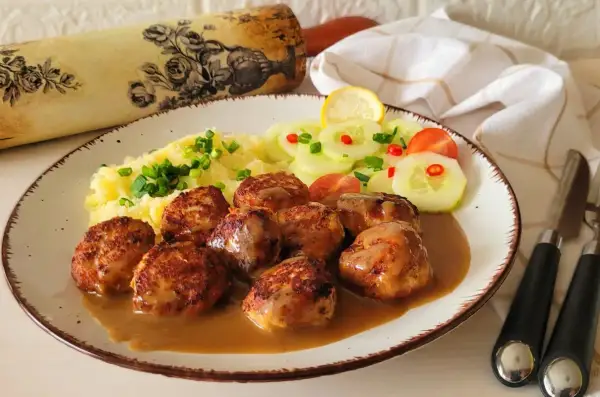 Pyszne pulpety szwedzkie w sosie, podane z puree ziemniaczanym i sałatką z ogórka.