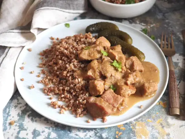 Pyszny gulasz z szynki podany z kaszą gryczaną i ogórkami kiszonymi. Aromatyczne danie, które zachwyci każdego smakosza.