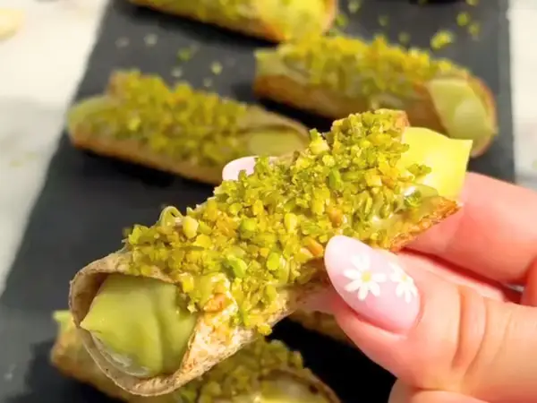 Chrupiące rurki wypełnione kremowym nadzieniem, obficie posypane zielonymi, aromatycznymi pistacjami. Te cannoli pistacjowe wyglądają niezwykle apetycznie.