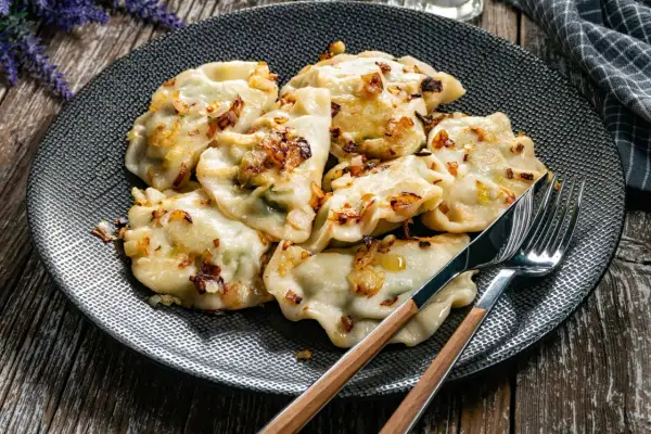 Pyszne pierogi z cebulką na talerzu. Czy pierogi gotować pod przykryciem? To pytanie zadaje sobie wielu kucharzy.