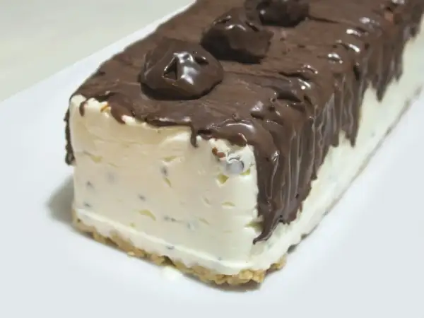 Pyszne lody sernikowe w kształcie bloku, oblane czekoladą z kawałkami czekolady na wierzchu.