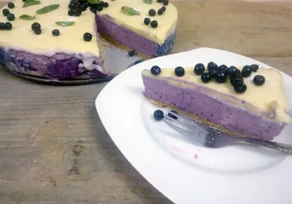 Pyszny sernik jagodowy na zimno z mascarpone, udekorowany świeżymi borówkami i listkami mięty. Idealny deser na letnie dni.