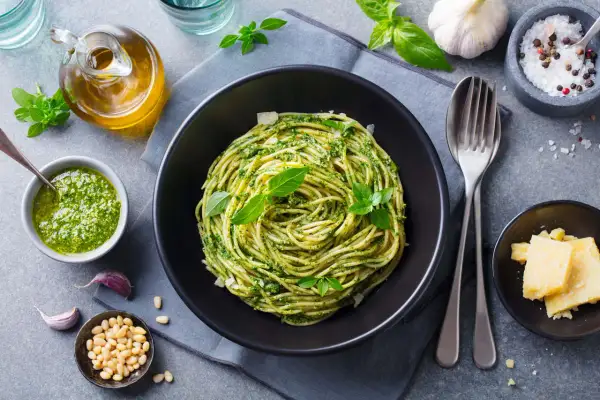 Pyszny piątkowy obiad bez mięsa: spaghetti z pesto, świeżą bazylią, orzeszkami pinii i parmezanem. Idealny na lekki posiłek.
