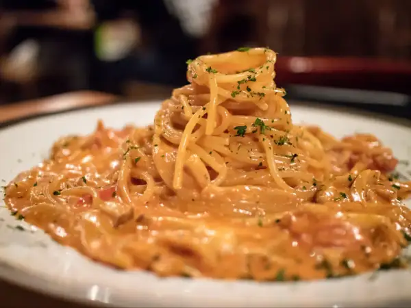 Pyszne spaghetti burrata w kremowym sosie, posypane zieloną pietruszką, czeka na spróbowanie.