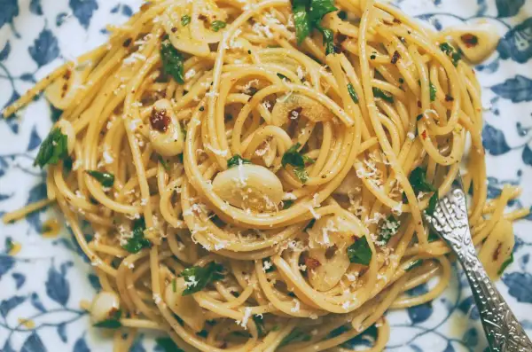 Pyszne spaghetti aglio olio z czosnkiem, natką pietruszki i płatkami chili, posypane parmezanem.