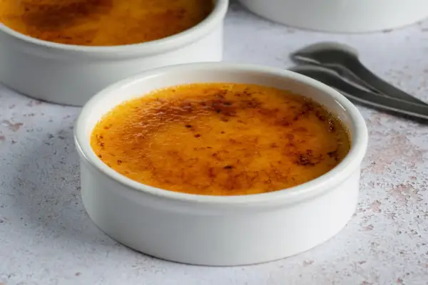 Dwa białe naczynia z pyszną, skarmelizowaną górą, idealne na deser crema catalana.
