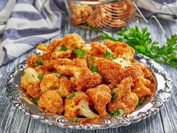 Chrupiące warzywa w panko, podane na ozdobnej tacy, posypane natką pietruszki. Idealna przekąska!