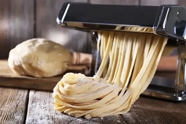Maszyna do makaronu tworzy świeże tagliatelle z ciasta. Idealny sposób, jak zrobić makaron w domu.
