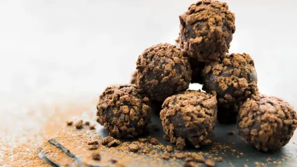 Stos pysznych, czekoladowych kulek Ferrero Rocher, posypanych kakao, kusi swoim wyglądem.