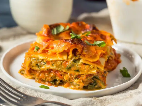 Pyszna lasagne wegetariańska z warzywami i sosem pomidorowym, udekorowana świeżą bazylią.