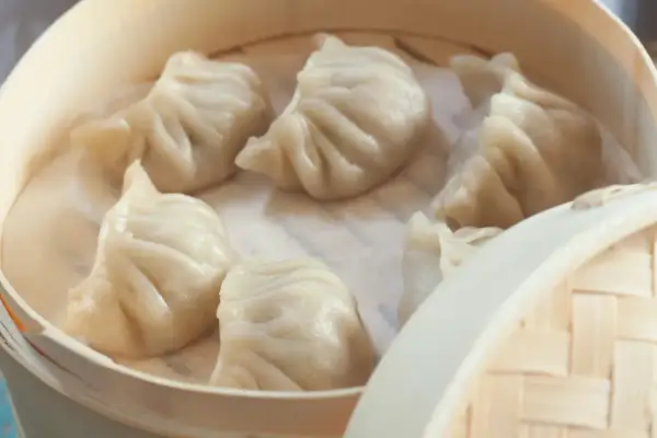 Pyszne pierożki na parze w bambusowym parowniku, gotowe do podania.