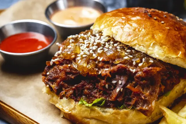 Sloppy Joe w bułce z sezamem, podany z ketchupem i sosem. Pyszne danie, które zachwyci każdego.